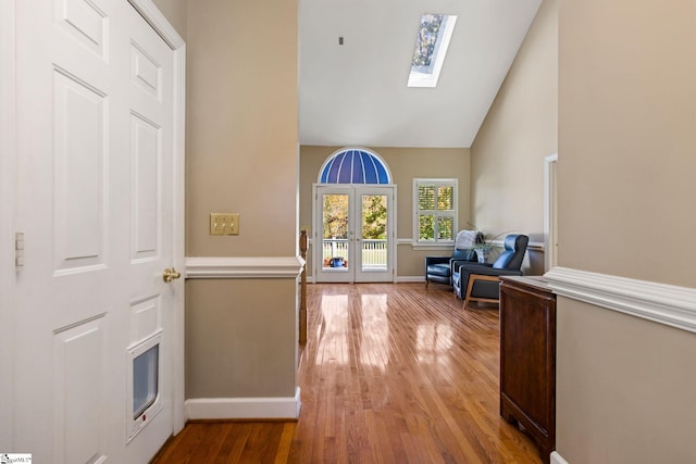 entrance foyer with french doors, light hardwood / wood-style floors, high vaulted ceiling, and a skylight