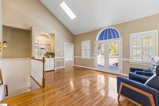 doorway to outside with french doors, wood-type flooring, high vaulted ceiling, and a skylight