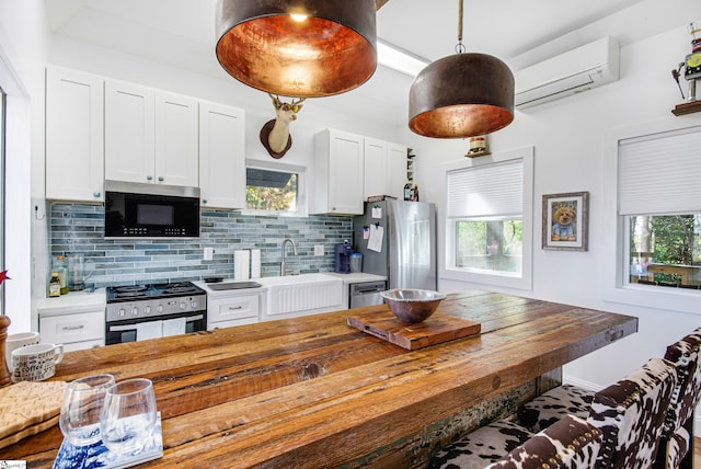 kitchen featuring tasteful backsplash, appliances with stainless steel finishes, wood counters, white cabinetry, and a wall mounted AC