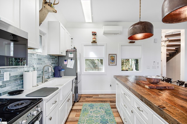 kitchen with a wall unit AC, backsplash, wood counters, pendant lighting, and light hardwood / wood-style floors