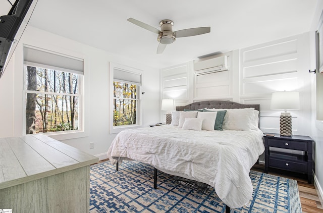 bedroom with ceiling fan, hardwood / wood-style flooring, and a wall mounted AC