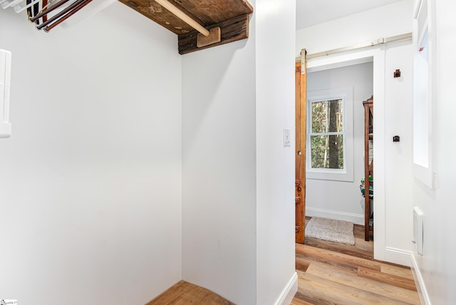 interior space with light hardwood / wood-style flooring, beam ceiling, and a barn door