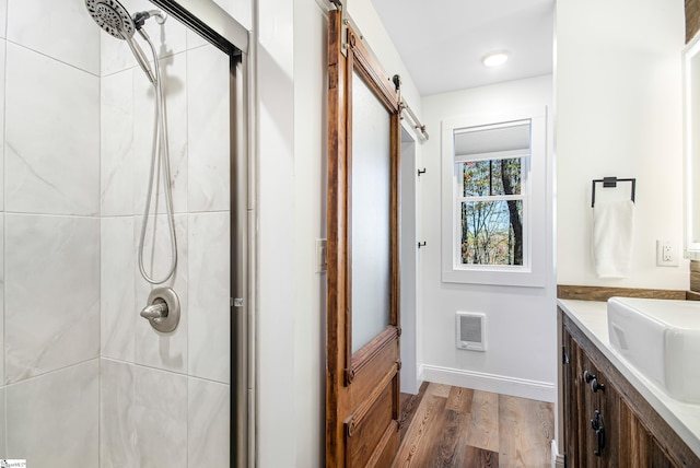 bathroom featuring vanity, wood-type flooring, heating unit, and tiled shower