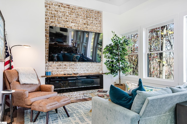 living room with a brick fireplace and hardwood / wood-style floors