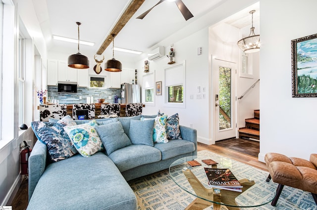 living room featuring beam ceiling, a wall mounted AC, hardwood / wood-style flooring, and plenty of natural light