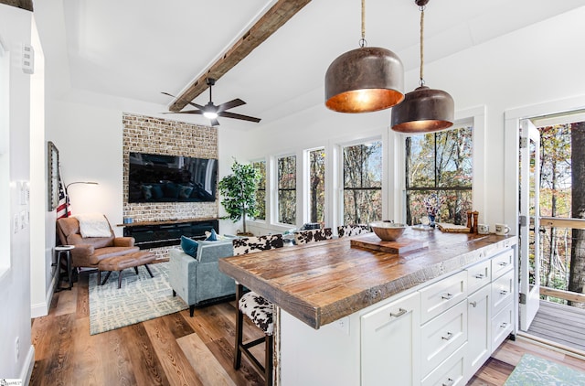 kitchen with white cabinets, a breakfast bar, hardwood / wood-style flooring, beamed ceiling, and pendant lighting