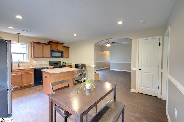 kitchen with a kitchen island, black appliances, pendant lighting, dark hardwood / wood-style flooring, and ceiling fan