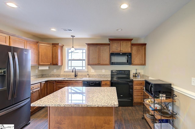 kitchen featuring black appliances, sink, a kitchen island, pendant lighting, and dark wood-type flooring