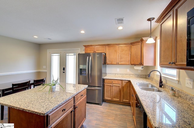 kitchen featuring light hardwood / wood-style flooring, sink, light stone countertops, stainless steel fridge with ice dispenser, and pendant lighting