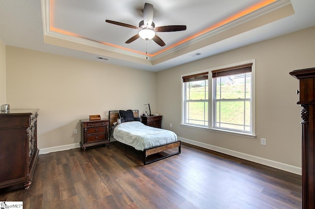 bedroom featuring ceiling fan, ornamental molding, a tray ceiling, and dark hardwood / wood-style flooring