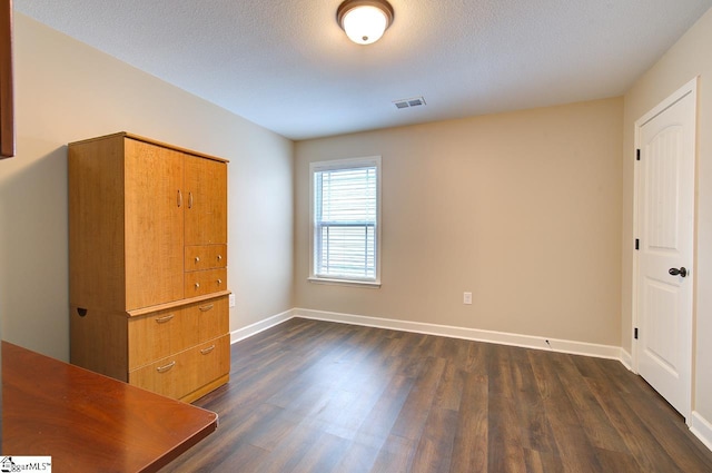 unfurnished bedroom featuring dark wood-type flooring and a textured ceiling