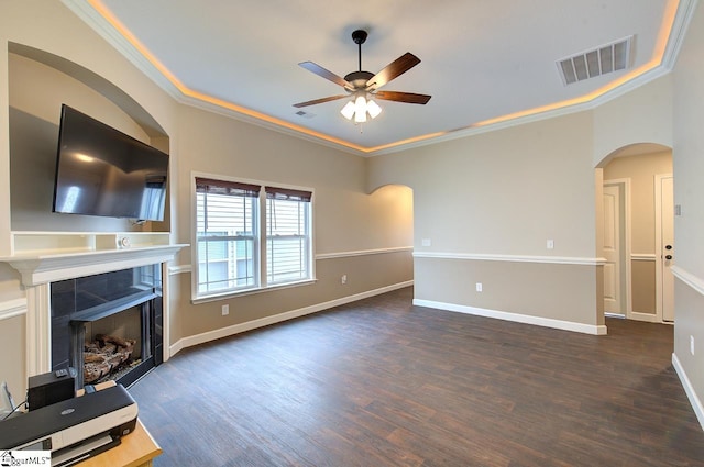 unfurnished living room with ornamental molding, ceiling fan, a tile fireplace, and dark hardwood / wood-style flooring