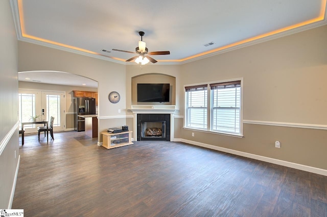 unfurnished living room featuring dark wood-type flooring, a fireplace, crown molding, and ceiling fan