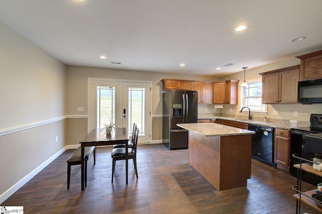 kitchen featuring black appliances, a center island, a wealth of natural light, and decorative light fixtures