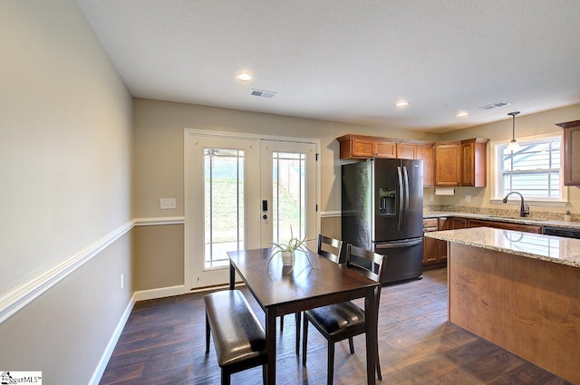 kitchen featuring stainless steel fridge, hanging light fixtures, plenty of natural light, and dark hardwood / wood-style floors