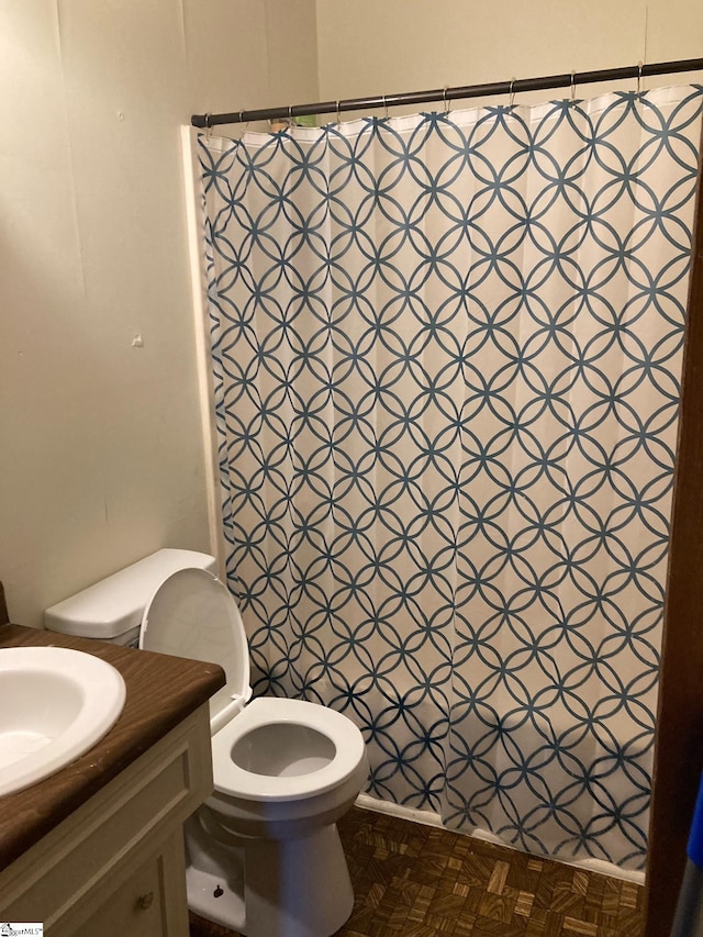 bathroom with vanity, toilet, parquet flooring, and walk in shower