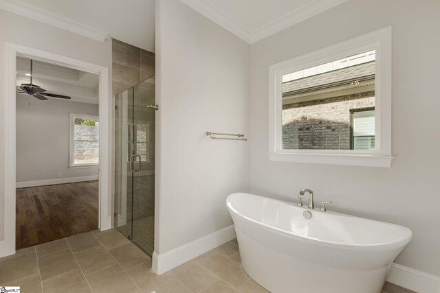 full bath with tile patterned flooring, baseboards, a soaking tub, a shower stall, and crown molding