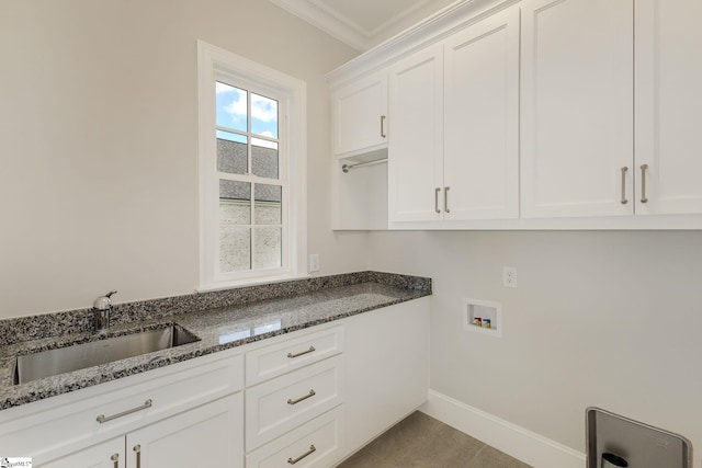 clothes washing area featuring washer hookup, crown molding, cabinet space, a sink, and baseboards