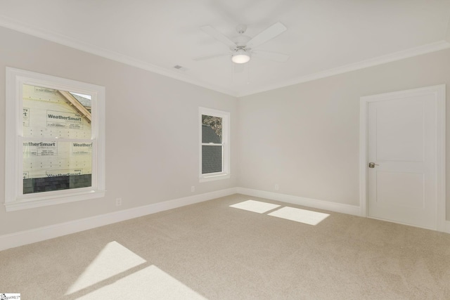 carpeted empty room featuring baseboards, a ceiling fan, and crown molding