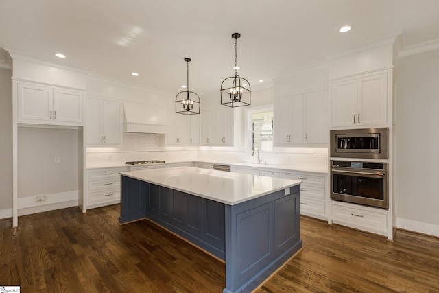 kitchen featuring white cabinets, custom range hood, appliances with stainless steel finishes, light countertops, and a sink