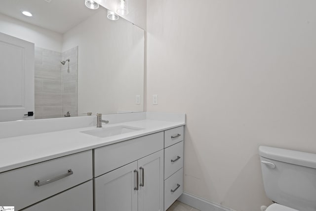 bathroom with toilet, vanity, and a tile shower