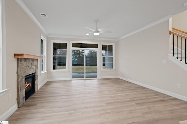 unfurnished living room with light hardwood / wood-style floors, ceiling fan, crown molding, and a stone fireplace