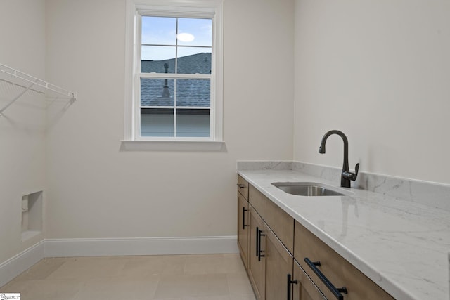 laundry room with a mountain view, light tile patterned floors, cabinets, and sink