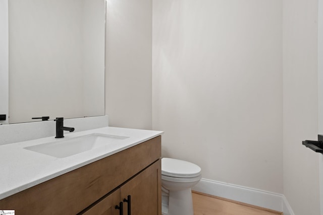 bathroom with toilet, vanity, and hardwood / wood-style flooring