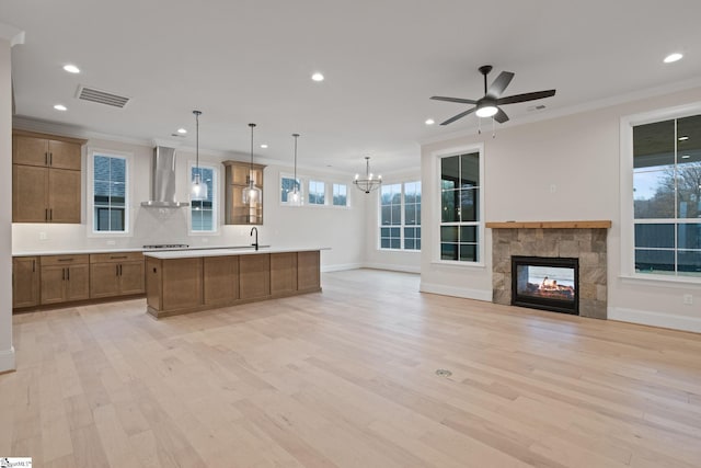 kitchen featuring pendant lighting, light hardwood / wood-style flooring, wall chimney exhaust hood, and a large island