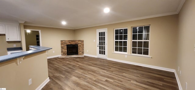 unfurnished living room featuring wood-type flooring, a stone fireplace, and ornamental molding