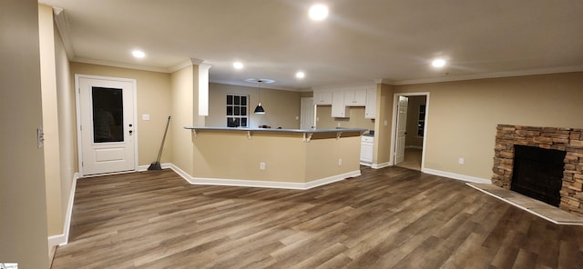 kitchen with dark hardwood / wood-style flooring, white cabinetry, a breakfast bar, and kitchen peninsula