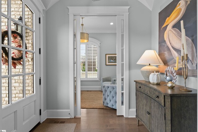 doorway to outside featuring dark wood-type flooring, lofted ceiling, and ornamental molding