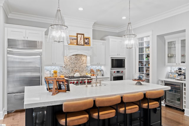 kitchen featuring stainless steel appliances, an inviting chandelier, beverage cooler, and white cabinetry