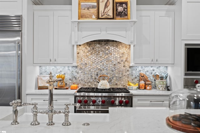 kitchen with tasteful backsplash, light stone counters, high quality appliances, and white cabinets