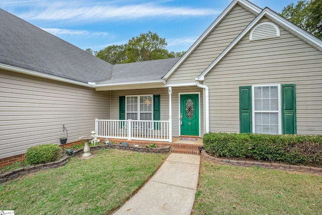 entrance to property with a porch and a yard