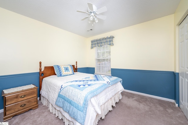 carpeted bedroom with a closet, ceiling fan, and a textured ceiling