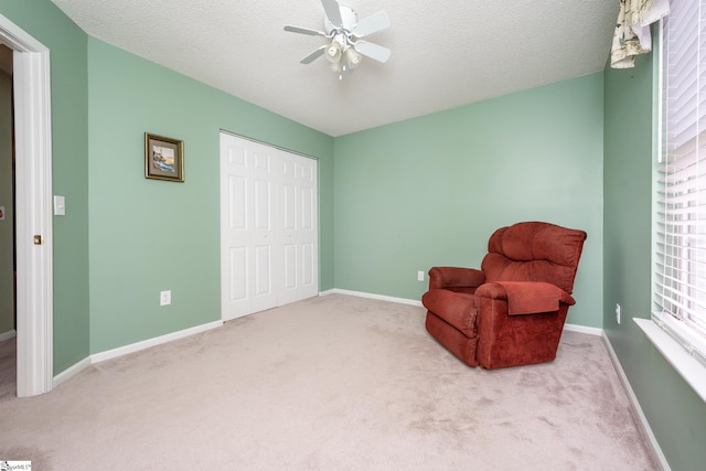 sitting room featuring light carpet, a textured ceiling, and ceiling fan