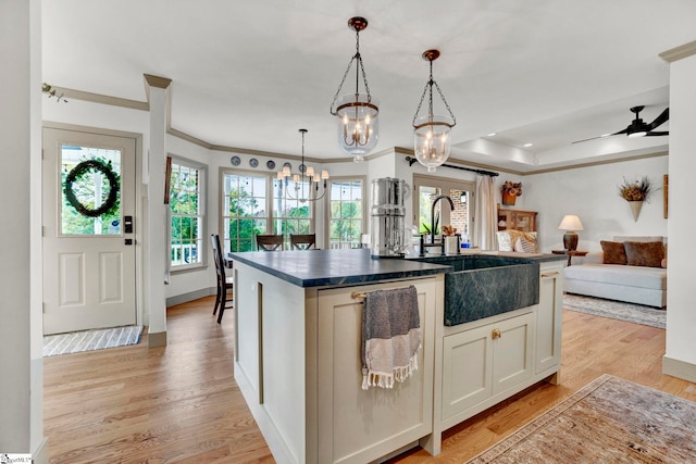 kitchen featuring sink, light hardwood / wood-style flooring, hanging light fixtures, and a kitchen island with sink