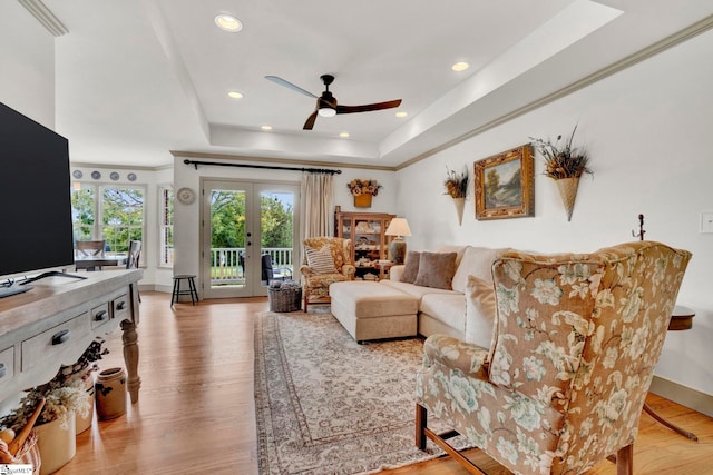 living room featuring french doors, light hardwood / wood-style floors, ceiling fan, and a tray ceiling