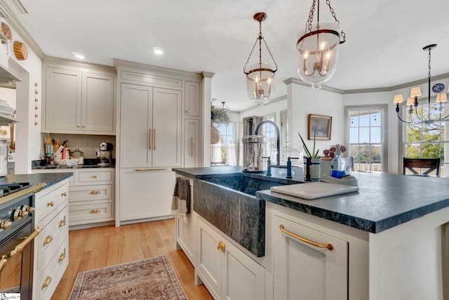 kitchen with crown molding, a kitchen island, pendant lighting, and light hardwood / wood-style floors