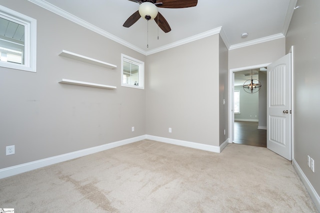 spare room featuring ornamental molding, light carpet, ceiling fan with notable chandelier, and a healthy amount of sunlight