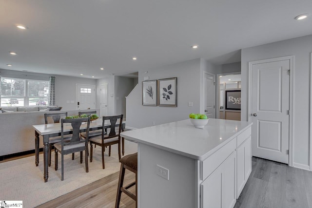 kitchen with white cabinetry, a center island, and light wood-type flooring