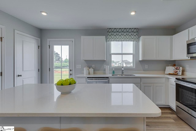 kitchen featuring white cabinetry, light hardwood / wood-style floors, appliances with stainless steel finishes, and a wealth of natural light