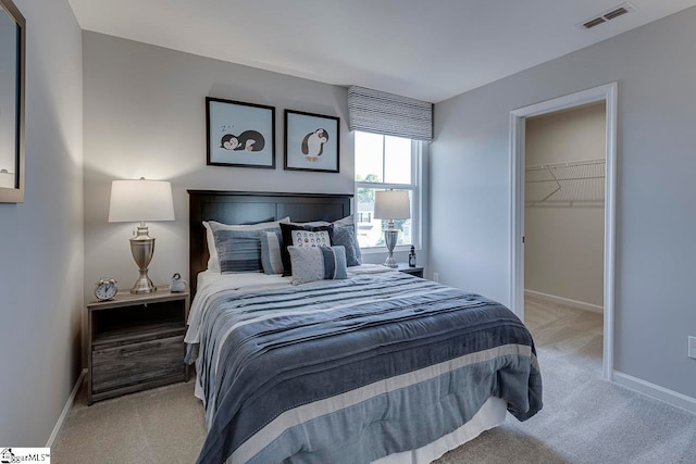 carpeted bedroom featuring a walk in closet and a closet