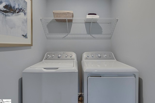 clothes washing area with separate washer and dryer and cabinets