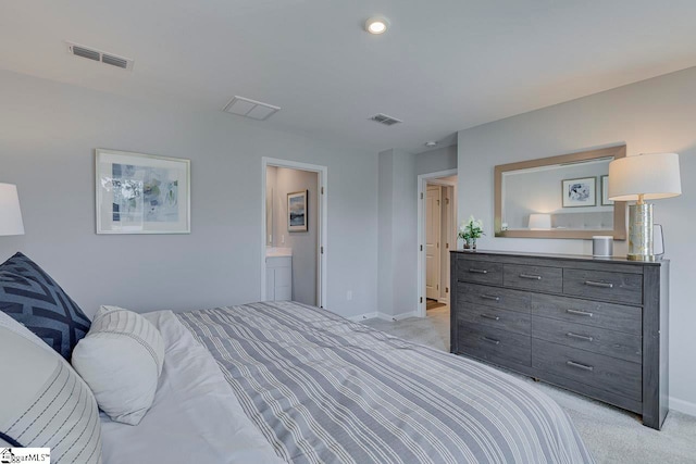 bedroom with ensuite bathroom and light colored carpet