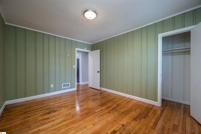 unfurnished bedroom with ornamental molding, a closet, and light hardwood / wood-style floors