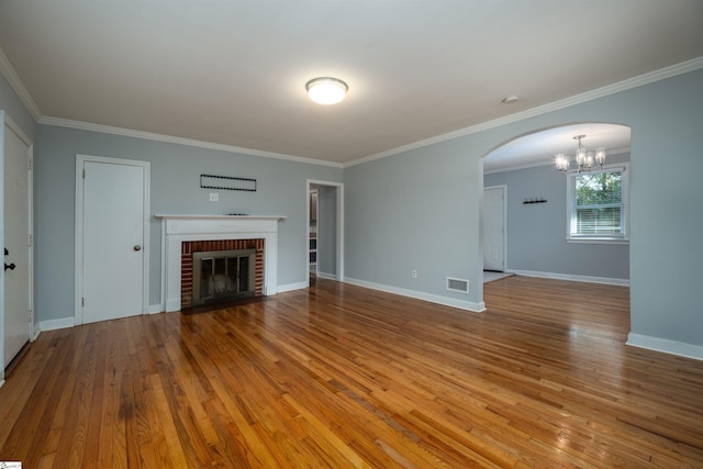 unfurnished living room with light hardwood / wood-style floors, crown molding, a notable chandelier, and a fireplace