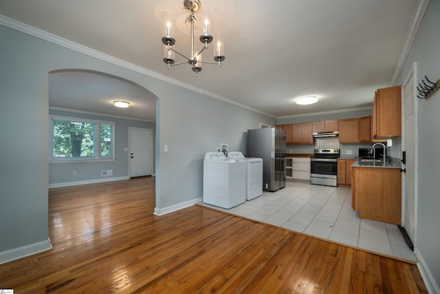 kitchen with appliances with stainless steel finishes, sink, light wood-type flooring, separate washer and dryer, and crown molding