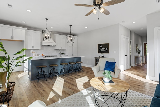 living room featuring light hardwood / wood-style floors, sink, and ceiling fan with notable chandelier